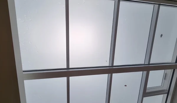 Solar safety and privacy window film applied to overhead glass skylight roofing for heat reduction, glass protection, and UV protection.